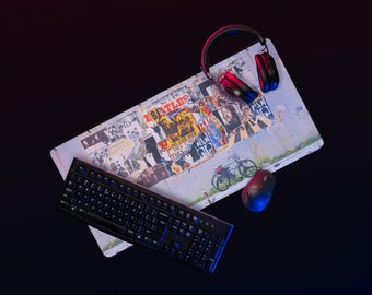 May include: A computer setup featuring a mouse, keyboard, and headphones. The mousepad displays a collage of The Beatles album art and posters. The keyboard is black, and the headphones are black and red.