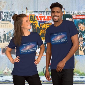 May include: Two people wearing navy blue t-shirts with a galaxy image and the text "JAI GURU DEVA... OM" and "NOTHING'S GONNA CHANGE MY WORLD".