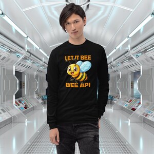 Puede incluir: Camiseta negra de manga larga con una abeja de dibujos animados y el texto "Let it bee bee api".