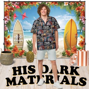 Puede incluir: Un hombre lleva una camisa hawaiana azul y negra con las palabras "His Dark Materials" impresas en ella. Está de pie frente a un telón de fondo de escena de playa con una tabla de surf y palmeras.