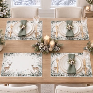 May include: A dining table set for four with rectangular placemats featuring a winter forest scene with deer, pine branches, and snowflakes. Each setting includes a white plate, a sage green cloth napkin, a gold fork, and a gold knife.