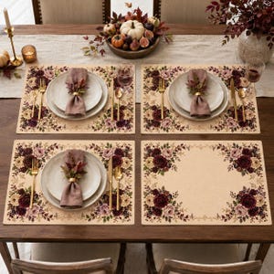 Op de afbeelding: Een set van vier rechthoekige placemats met een crèmekleurige basis en een bloemenrand van dieprode en zachtroze rozen, groene bladeren en kleine vijgen. Elke placemat is versierd met een bijpassend servet, een gouden ring en bestek.