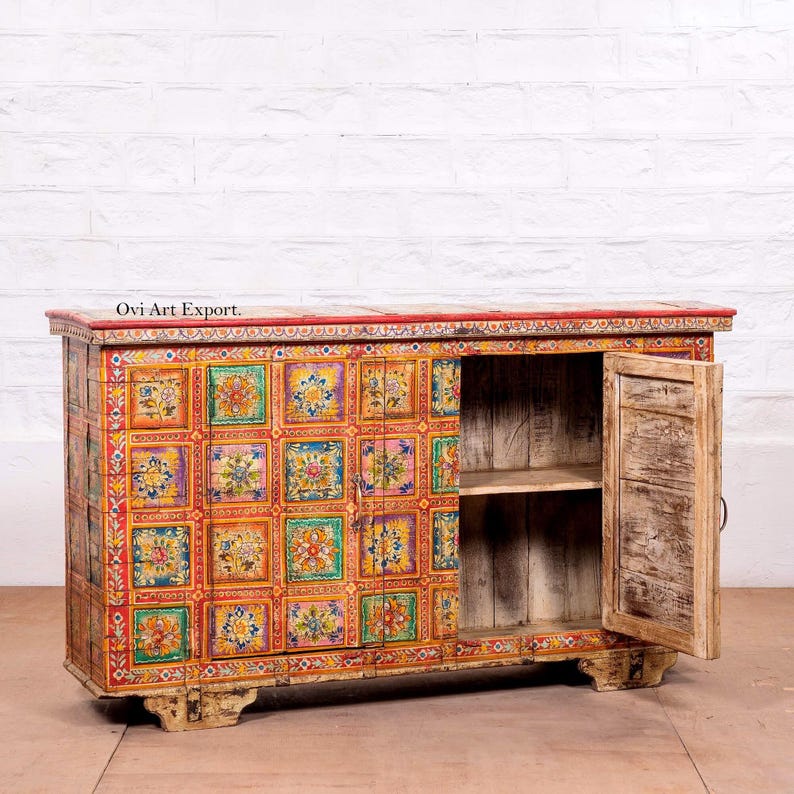 Puede incluir: Un aparador de madera pintado a mano con una parte superior roja y patrones cuadrados florales. Una puerta est&aacute; abierta, revelando un estante en el interior. El mueble es una pieza &uacute;nica con un aspecto vintage y desgastado. Aproximadamente 150 cm de ancho.