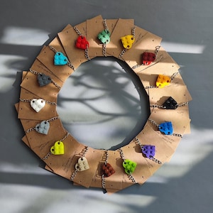 May include: A circle of brown cards with colorful heart-shaped charms made of plastic building blocks. Each charm is a different color, including red, blue, green, yellow, and orange.