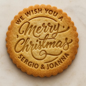 Peut inclure: Un biscuit rond doré aux bords festonnés, portant le texte en relief WE WISH YOU A Merry Christmas SERGIO & JOANNA. La surface présente une texture cuite lisse avec les lettres clairement imprimées au centre du biscuit.