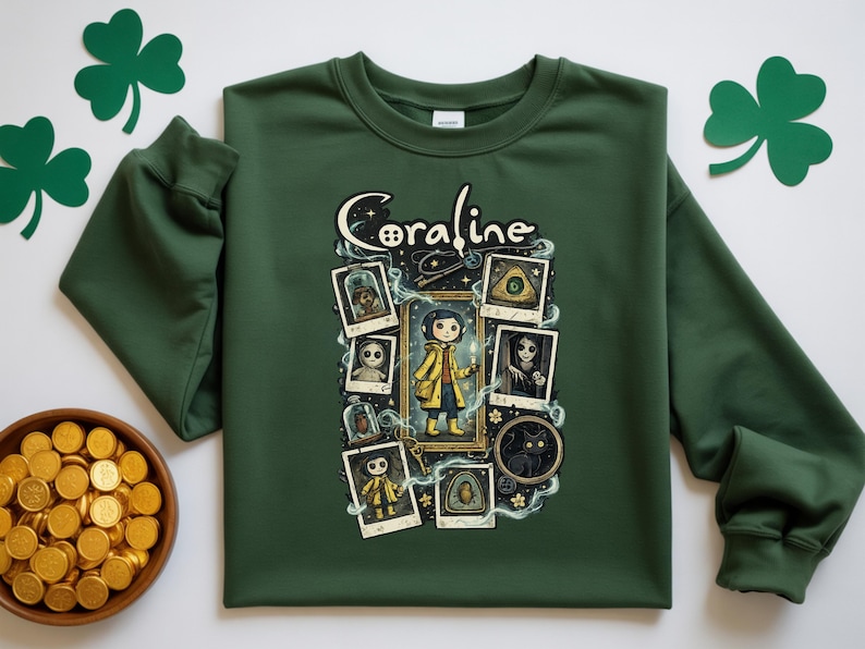 Op de afbeelding: Een bosgroene sweater met ronde hals en een grafische print met de tekst Coraline. Het ontwerp bevat een centrale illustratie van een personage in een gele regenjas, omringd door diverse ingelijste polaroid-stijl afbeeldingen en magische rook.