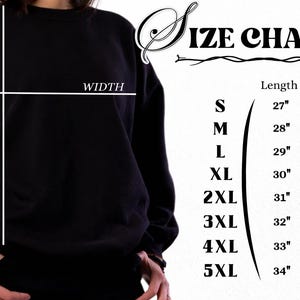 Op de afbeelding: Een zwart sweatshirt met ronde hals naast een maattabel. De tabel toont de maten S tot en met 5XL met de bijbehorende lengte- en breedtematen in inches, vari&euml;rend van 27 bij 20 inch tot 34 bij 34 inch.