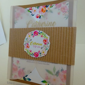 Puede incluir: Una tarjeta marrón con un diseño floral blanco y una superposición transparente. La tarjeta tiene el texto "Catherine Vanes" en letras doradas y una corona de flores con el nombre "Catherine Vanes" en el centro.