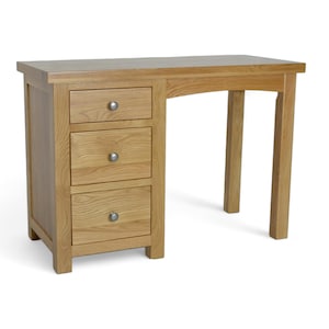 May include: A light oak desk with three drawers on the left and a single leg on the right. The desk has a rectangular top and silver knobs on the drawers. The desk measures approximately 120 cm in length.