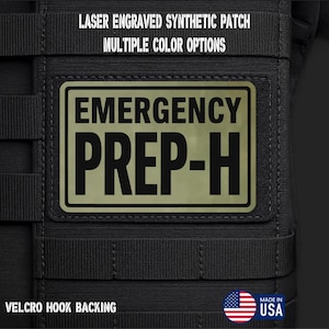 May include: A rectangular laser-engraved synthetic patch with a black border and olive green background. The text EMERGENCY PREP-H is printed in bold black capital letters. The patch features a Velcro hook backing and is attached to black webbing.