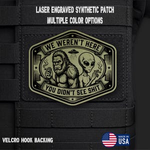 May include: A rectangular olive green synthetic patch with a laser-engraved graphic of Bigfoot and an alien smoking, featuring a UFO and the text WE WEREN'T HERE YOU DIDN'T SEE SHIT. The patch has a hook backing and is attached to black tactical gear.