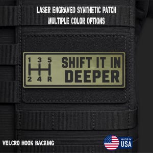 May include: A rectangular olive green synthetic patch with a black laser-engraved manual transmission gear shift pattern and the text SHIFT IT IN DEEPER. The patch features a hook backing and is displayed on a black tactical gear surface.