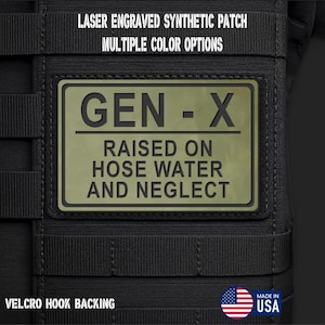 May include: A rectangular olive green synthetic patch with black laser-engraved text reading GEN-X RAISED ON HOSE WATER AND NEGLECT. The patch is attached to a black tactical gear surface with horizontal webbing straps and features a velcro hook backing.