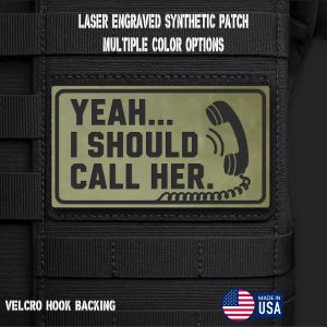 May include: A rectangular olive green synthetic patch with a black border and black text that reads YEAH... I SHOULD CALL HER. The design includes a graphic of a vintage telephone handset with a cord. The patch features a hook backing.