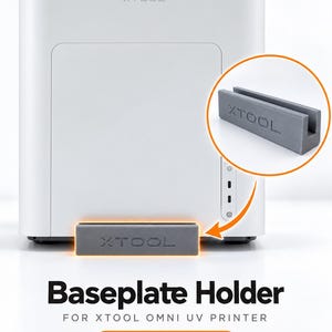 May include: A gray rectangular baseplate holder with the text XTOOL embossed on the front. The holder features a vertical slot designed to store one baseplate for the XTOOL Omni UV printer, shown in front of the white printer unit.
