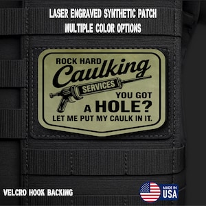 May include: A rectangular patch with the text "ROCK HARD Caulking SERVICES YOU GOT A HOLE? LET ME PUT MY CAULK IN IT." The patch is olive green with black text and a caulk gun graphic. The patch is on a black background with the text "LASER ENGRAVED SYNTHETIC PATCH MULTIPLE COLOR OPTIONS" at the top.