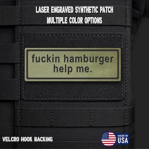 May include: A rectangular olive green synthetic patch with a black border and the laser-engraved text "fuckin hamburger help me." The patch is attached to a black tactical gear surface with a hook backing. Text above reads "LASER ENGRAVED SYNTHETIC PATCH MULTIPLE COLOR OPTIONS" and "VELCRO HOOK BACKING."