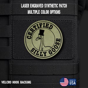 May include: A round, olive green patch with the words "CERTIFIED SILLY GOOSE" encircling a cartoon goose wearing a top hat. The patch is laser engraved and made of synthetic material. The text "LASER ENGRAVED SYNTHETIC PATCH MULTIPLE COLOR OPTIONS" is at the top. It has Velcro hook backing.