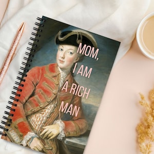 May include: A spiral bound notebook featuring a vintage portrait of a man in a red and gold uniform. The text "MOM, I AM A RICH MAN" is printed in pink on the cover.