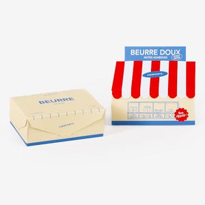 Peut inclure: Deux boîtes de notes adhésives. L'une est une boîte jaune clair avec le mot "BEURRE" imprimé dessus. L'autre est une boîte d'exposition avec des rayures rouges et blanches et les mots "BEURRE DOUX" et "Bon appétit!" imprimés dessus.