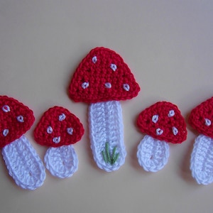 Peut inclure: Cinq champignons en crochet rouge et blanc avec des tiges blanches. Les champignons ont des points blancs sur les chapeaux rouges.