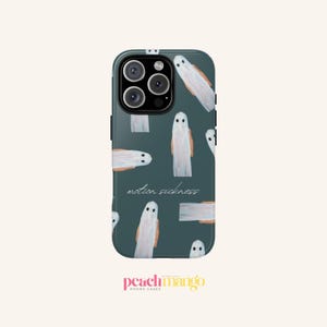 Può includere: Una custodia per telefono verde acqua con un motivo di illustrazioni di fantasmi bianchi con dettagli arancioni. Le parole "motion sickness" sono scritte in corsivo. Il marchio "peachmango" è in basso.
