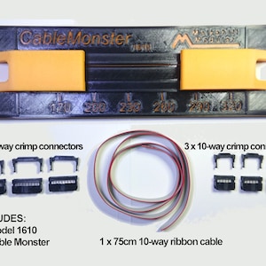 Puede incluir: Un kit Cable Monster Modelo 1610 negro y naranja. Incluye una herramienta de crimpado negra con soportes naranjas, 3 conectores de crimpado de 16 vías y 3 de 10 vías, y un cable plano de 75 cm. La herramienta tiene medidas en milímetros.