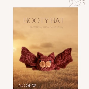 May include: A crocheted bat plush toy with a burgundy body and brown face. The toy is sitting in a field of tall grass. The text "BOOTY BAT" and "PATTERN by @Crochet_Crochey" is at the top of the image. The text "NO SEW" is at the bottom of the image.