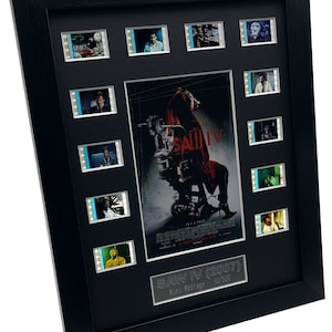 May include: A black framed movie prop display featuring a poster for the film "Saw IV (2007)" with a pig-masked figure in a chair. The display includes 10 film cell strips with scenes from the movie. The display is numbered 10/500.