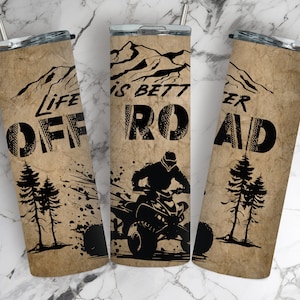 May include: Three stainless steel tumblers with a brown and black design. The tumblers feature a mountain scene with the text "Life is Better Off Road".