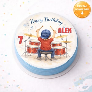May include: A round cake with blue frosting and a printed image. The image features a cartoon drummer with a red shirt and blue hat playing a drum set. Text includes "Happy Birthday ALEX" and the number "7". A digital download icon is in the corner.
