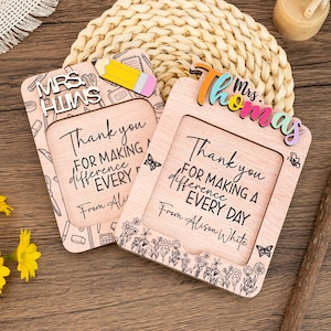 Può includere: Due cornici in legno per l'apprezzamento degli insegnanti. Una cornice ha il nome "Mrs. Huns" e l'altra "Mrs. Thomas". Entrambe le cornici hanno il messaggio "Grazie per aver fatto la differenza ogni giorno".
