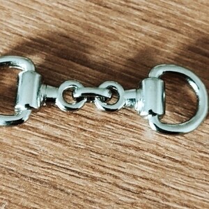 May include: A silver metal snap hook with two loops on either end, connected by a chain with three links.