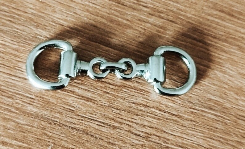 May include: A silver metal snap hook with two loops on either end, connected by a chain with three links.