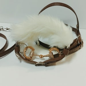 May include: Brown leather horse halter with a white fur trim and a gold-tone metal bit.