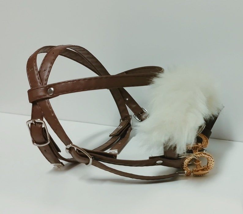 May include: A brown leather dog muzzle with a white fur trim and gold metal accents.