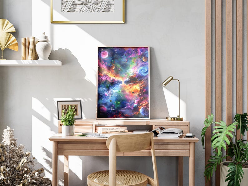May include: A framed art print depicting a vibrant, colorful nebula with planets and swirling galaxies. The artwork features shades of blue, purple, orange, and green. The print is displayed on a wooden desk with a small lamp and a potted plant.