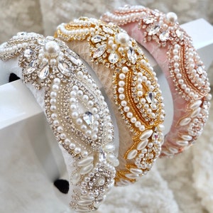 Pode incluir: Três tiaras adornadas em branco, dourado e rosa. Cada tiara é adornada com pérolas e cristais. A tiara branca tem detalhes prateados, a dourada tem detalhes dourados e a rosa tem detalhes em ouro rosa.