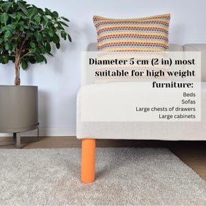 Puede incluir: Una pata de mueble naranja, de 5 cm de di&aacute;metro, sostiene un sof&aacute; color crema. Una almohada decorativa con un colorido estampado de puntos descansa sobre el sof&aacute;. El texto indica que la pata es adecuada para muebles pesados como camas, sof&aacute;s y armarios.