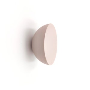 May include: A light pink ceramic bowl with a smooth, rounded shape. The bowl is empty and appears to be made of a matte finish.