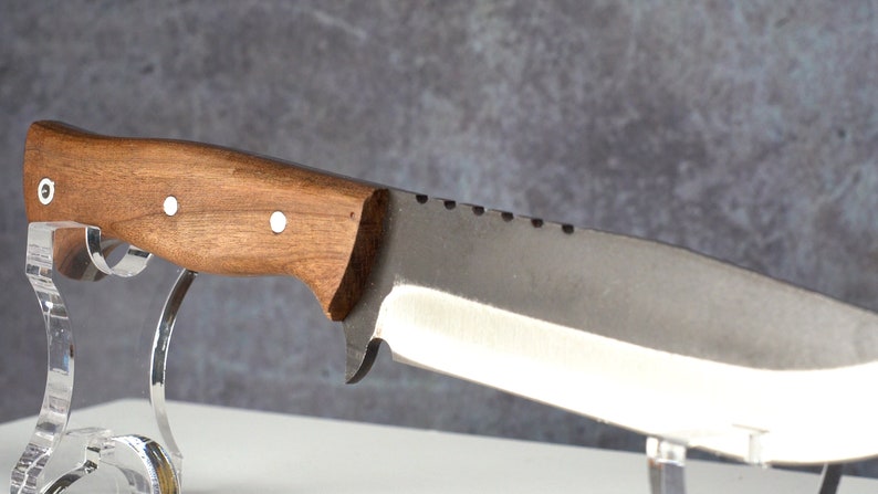 May include: A knife with a brown wooden handle and a silver blade. The blade has a serrated edge and a small notch near the handle.