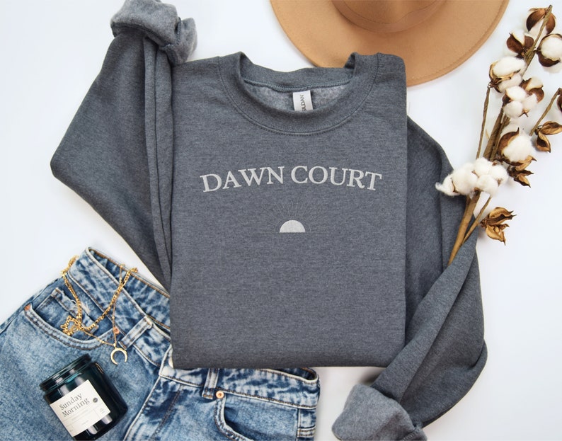 May include: A dark grey sweatshirt with the text "DAWN COURT" in white lettering and a small white crescent moon graphic.
