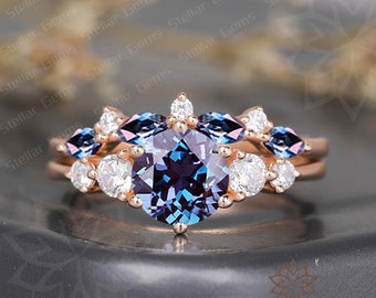 May include: A rose gold engagement ring set with a large round alexandrite center stone surrounded by smaller round diamonds and marquise alexandrite stones.