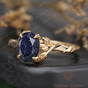 May include: A gold ring with a blue gemstone set in a leaf-shaped band.