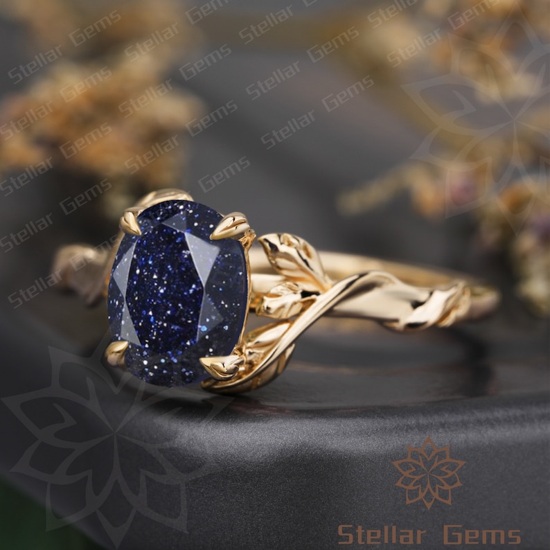 May include: A gold ring with a blue gemstone set in a leaf-shaped band.