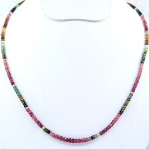 Könnte beinhalten: Eine Halskette aus bunten Edelsteinperlen. Die Kette besteht aus kleinen, facettierten Perlen in Rosa-, Grün-, Gelb- und Schwarztönen. Die Perlen sind zu einer zarten, eleganten Halskette aufgereiht.