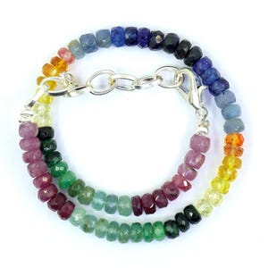 May include: A rainbow gemstone bracelet with a silver clasp. The bracelet features beads in shades of blue, green, yellow, orange, red, and purple.