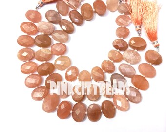 May include: Strands of faceted, oval-shaped beads in shades of peach, tan, and brown. Each strand is finished with a peach-coloured tassel. The beads are strung together, creating a layered effect. The text "PINK CITY BEADS" is visible.