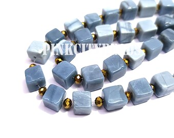 Puede incluir: Cadenas de cuentas cúbicas azul claro con efecto veteado, intercaladas con pequeñas cuentas facetadas doradas. Las cuentas están ensartadas, creando un collar o pulsera.