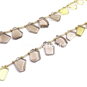 May include: Two strands of gemstone beads. One strand features smoky quartz-colored, geometric-shaped beads. The other strand has light yellow-green, rectangular beads. Both strands have small gold-colored beads between the gemstones.